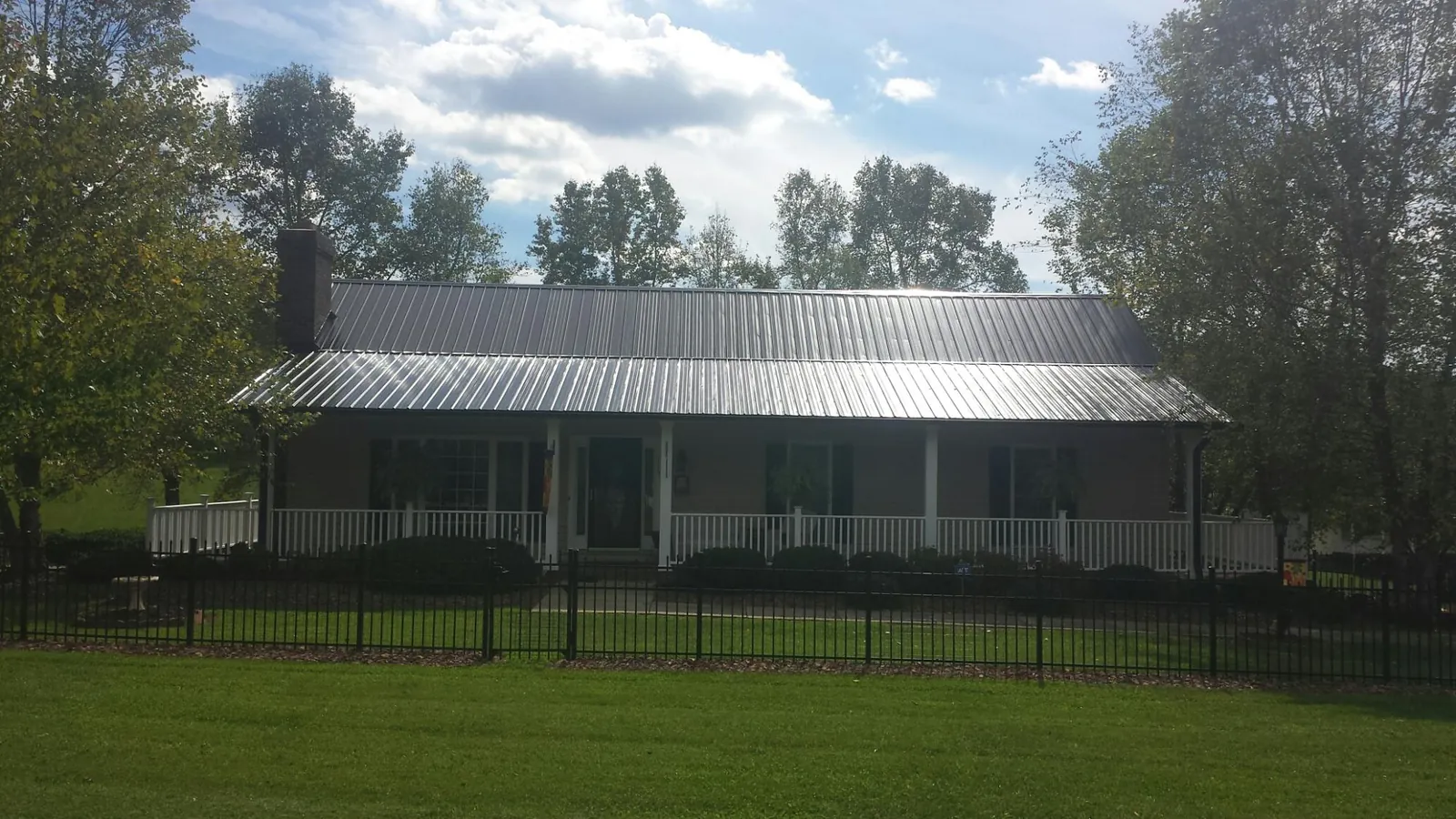 Gray metal roof on a brick ranch with a full width front porch — Gutter Guard Installation work by our crew in Hereford