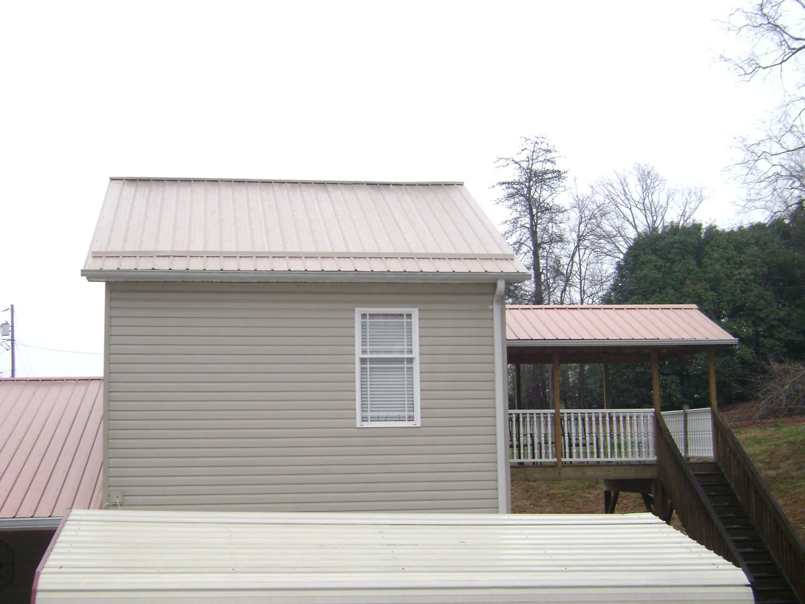Tan metal roofs on a two story addition and attached porch, from a Roof Replacement job in Hereford